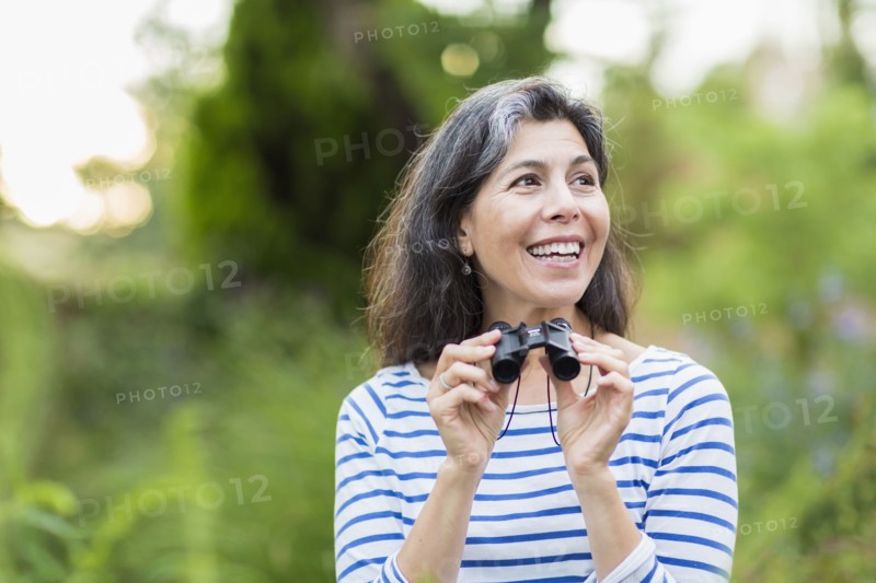 Hispanic woman using binoculars outdoors