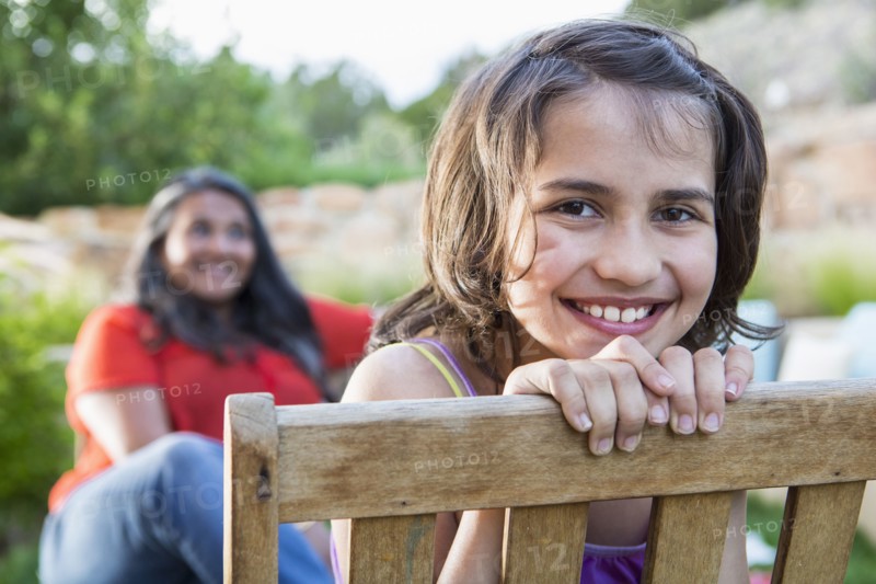 Girl smiling in wooden chair outdoors