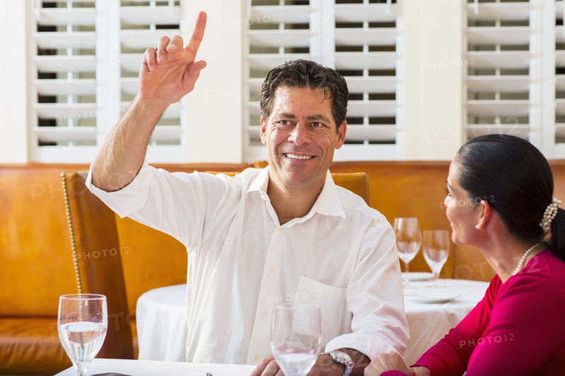 Couple calling waiter at restaurant