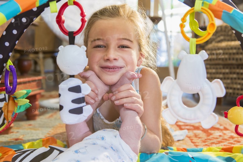 Caucasian girl playing with newborn baby brother