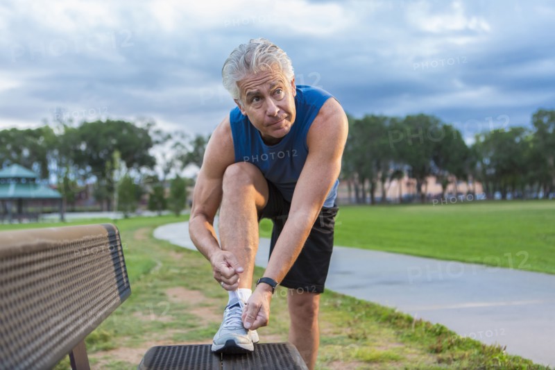 Hispanic man tying shoe in park
