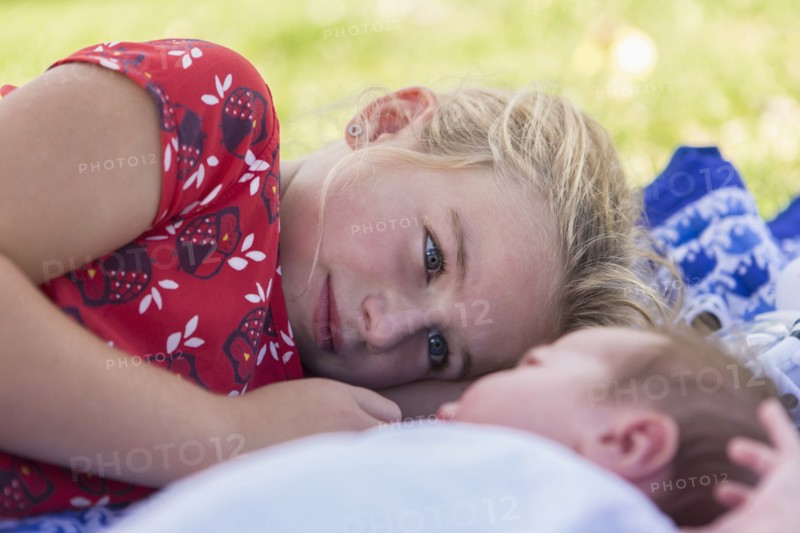 Caucasian girl laying with newborn baby brother