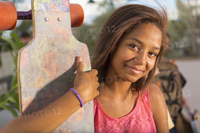 Mixed race teenage girl holding skateboard outdoors