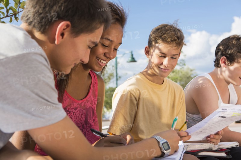 Teenagers doing homework together outdoors