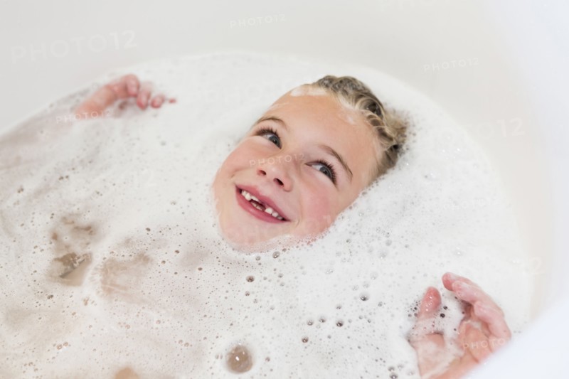 Caucasian girl laying in bubble bath