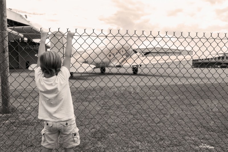 Boy climbing chain link fence around airport