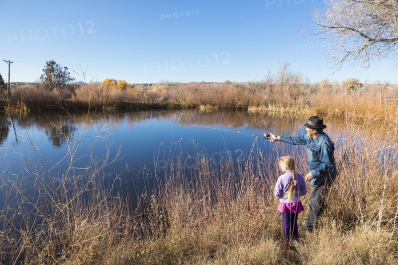 Senior man and granddaughter watching calm lake