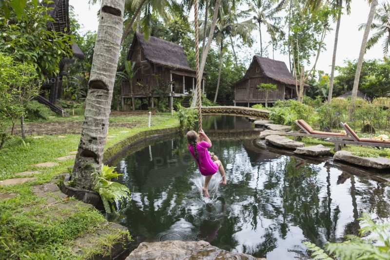 Caucasian girl swinging on rope in garden