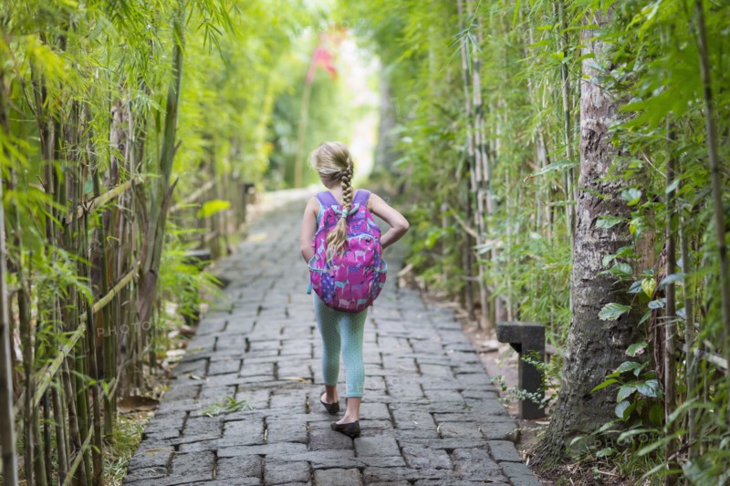 Caucasian girl walking on stone path among bamboo trees