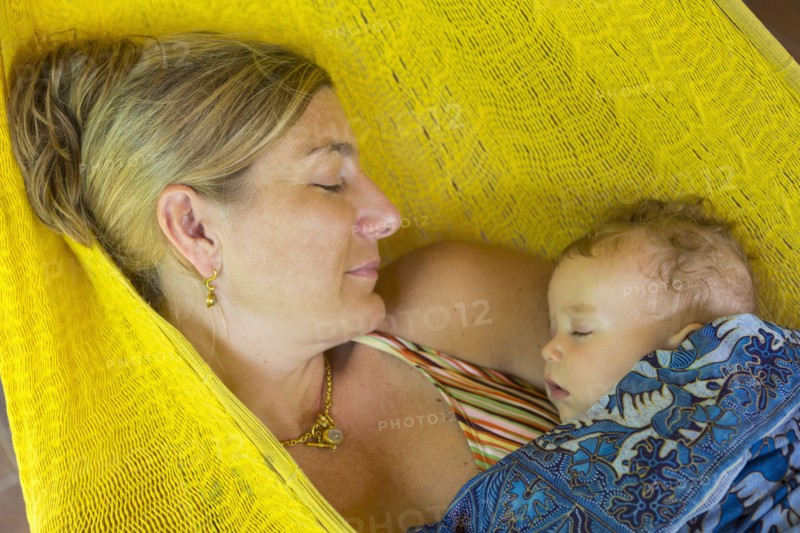 Caucasian mother and baby sleeping in hammock