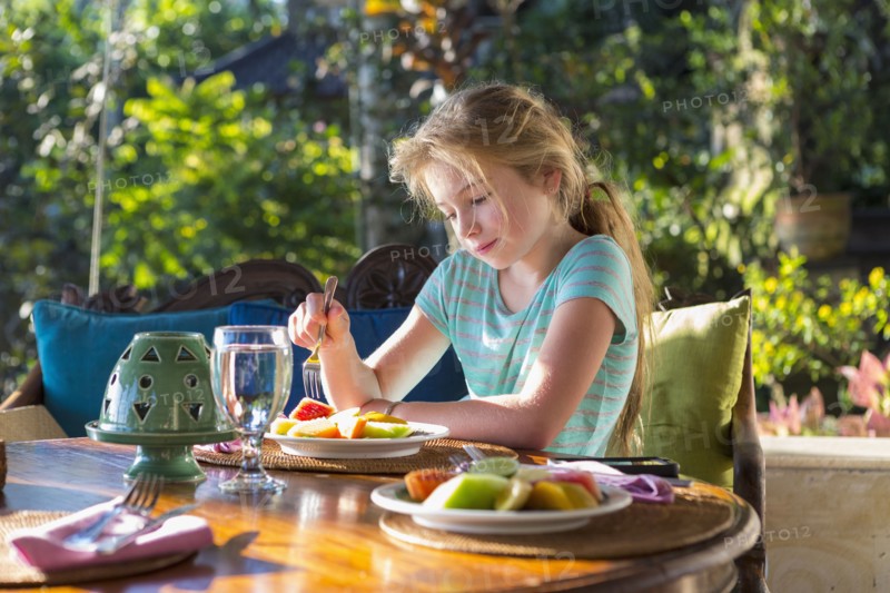 Caucasian girl eating breakfast at table