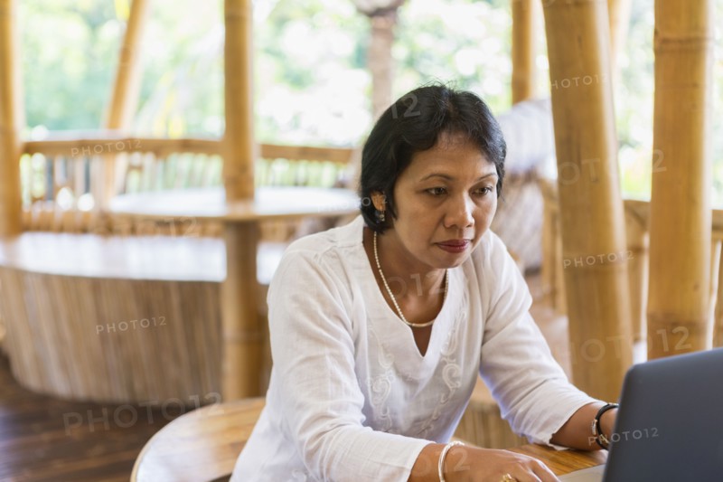 Balinese woman using laptop at table