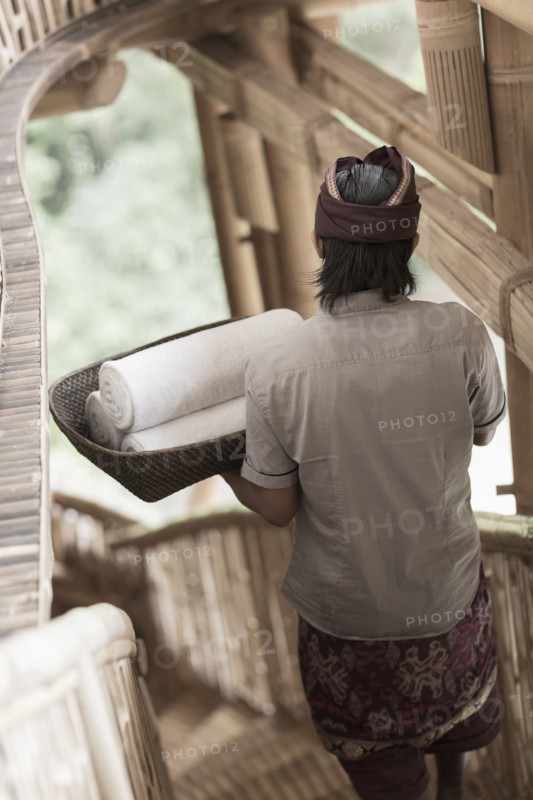 Balinese man carrying rolled towels in hotel