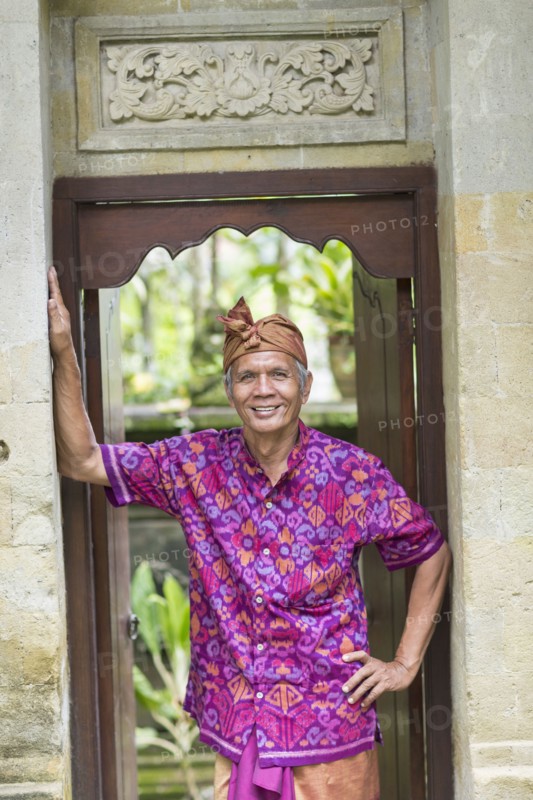 Balinese worker smiling in wood archway