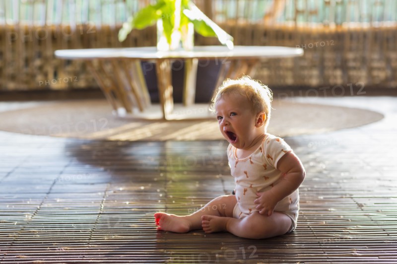 Caucasian baby yawning on floor