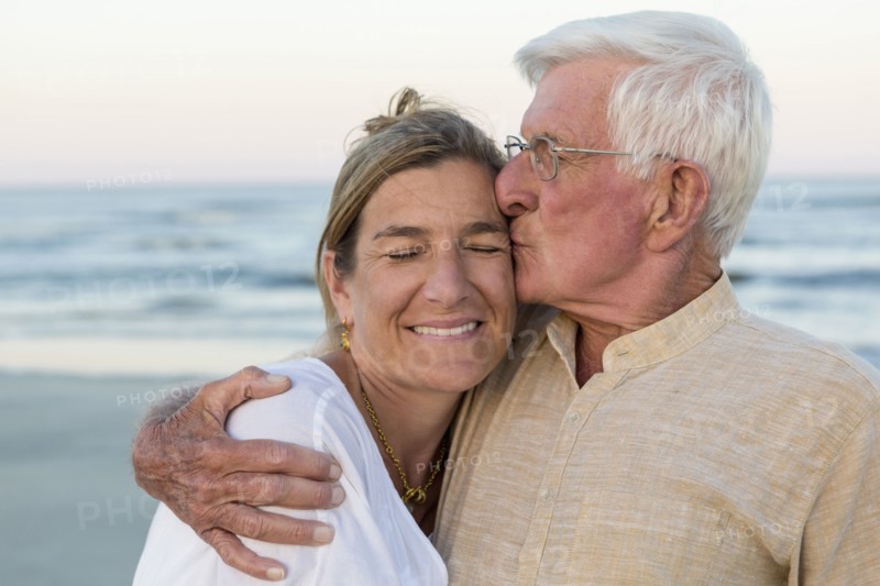 Caucasian father kissing daughter on beach