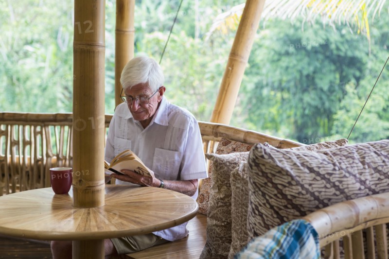 Older Caucasian man reading in bamboo living room