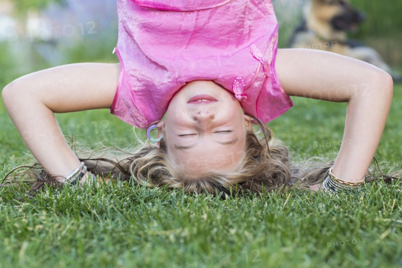 Caucasian girl doing headstand in grass