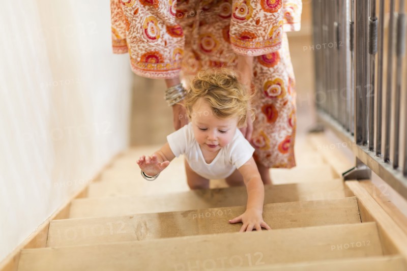 Caucasian mother helping baby son climb stairs