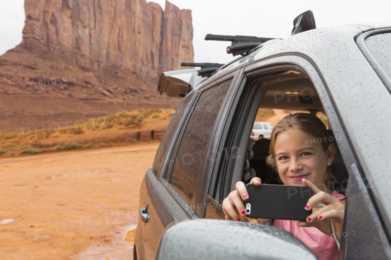 Caucasian girl taking cell phone photograph from car