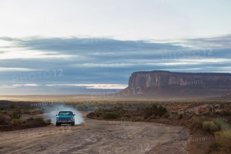 Car driving on dirt road in desert