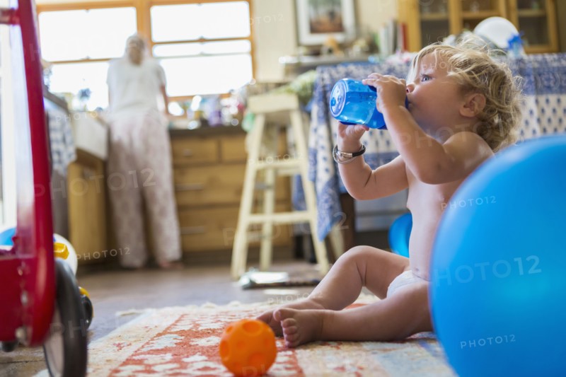 Caucasian baby boy drinking water in kitchen