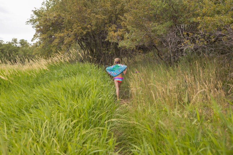 Caucasian girl carrying towel in tall grass