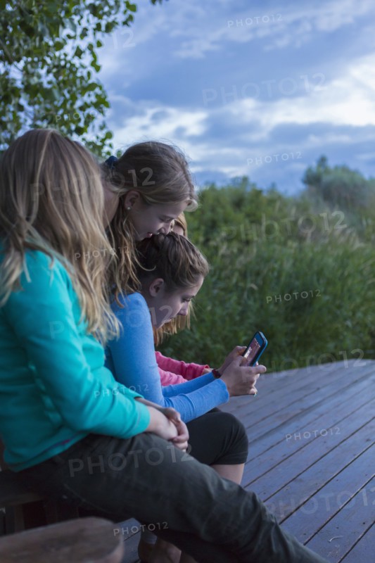 Children using cell phone together outdoors