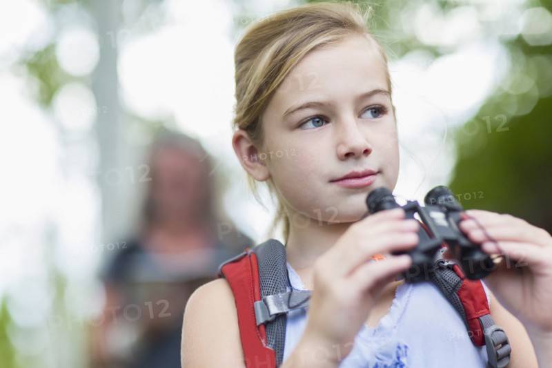 Caucasian girl using binoculars in forest