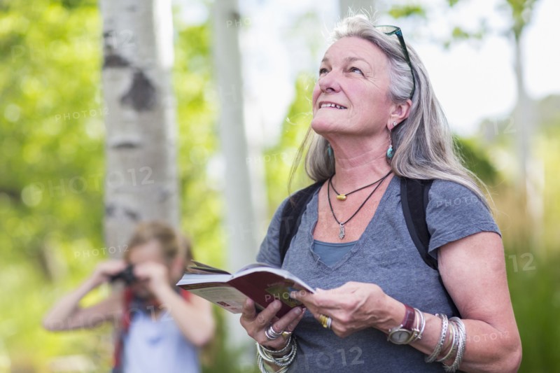 Caucasian senior woman carrying guidebook in forest