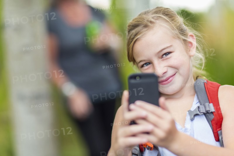 Caucasian girl taking cell phone photograph in forest