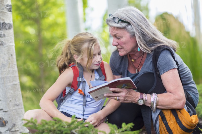 Caucasian grandmother and granddaughter reading guidebook while hiking