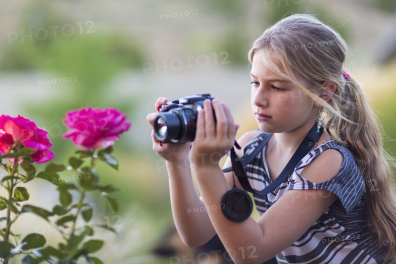 Caucasian girl photographing flowers outdoors