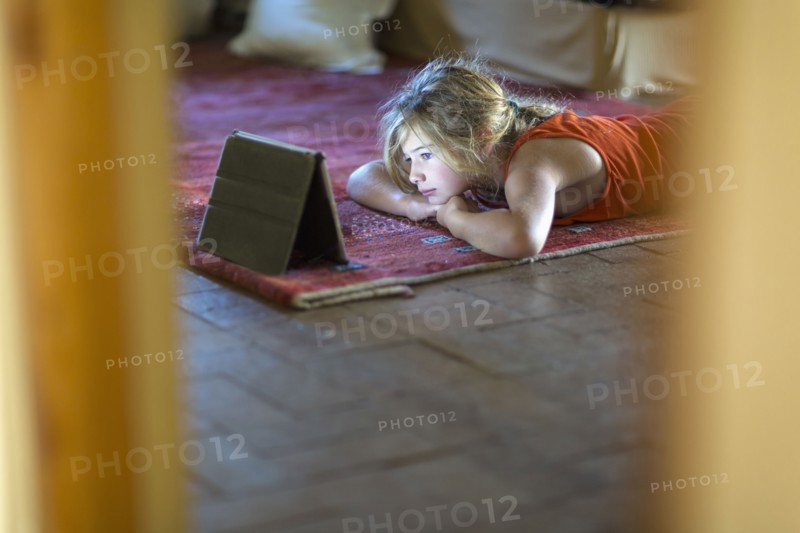 Caucasian girl watching digital tablet on floor