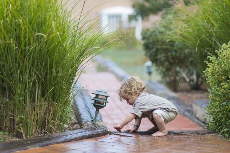 Caucasian baby boy playing on brick walkway