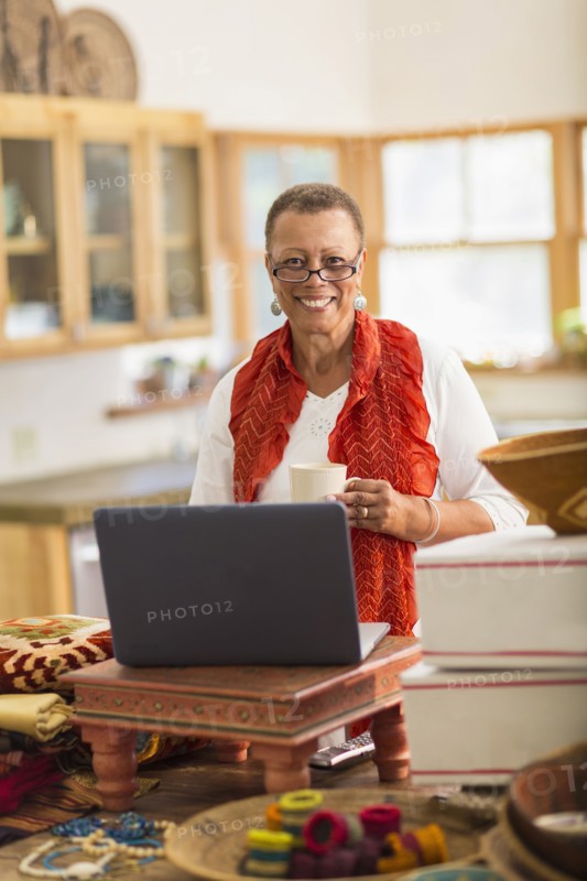Older mixed race woman using laptop in home office