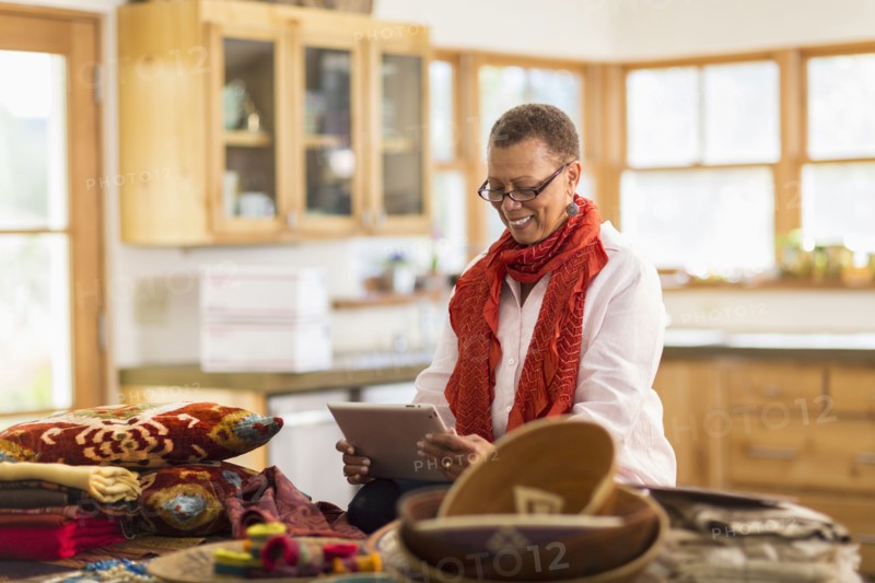 Older mixed race woman using digital tablet in home office