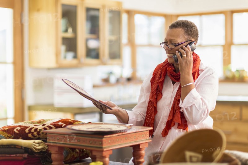 Older mixed race woman talking on telephone in home office