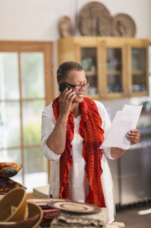 Older mixed race woman talking on telephone in home office