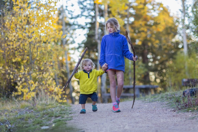 Caucasian children hiking on dirt path in forest
