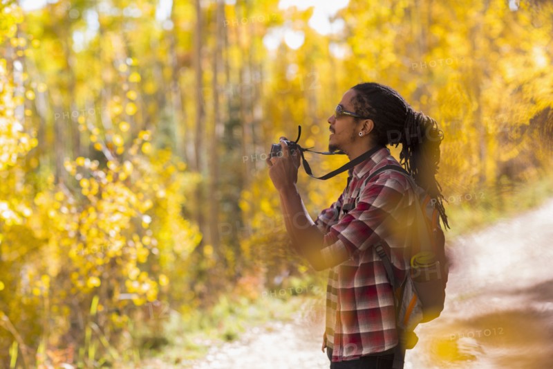 Mixed race hiker taking photograph in forest