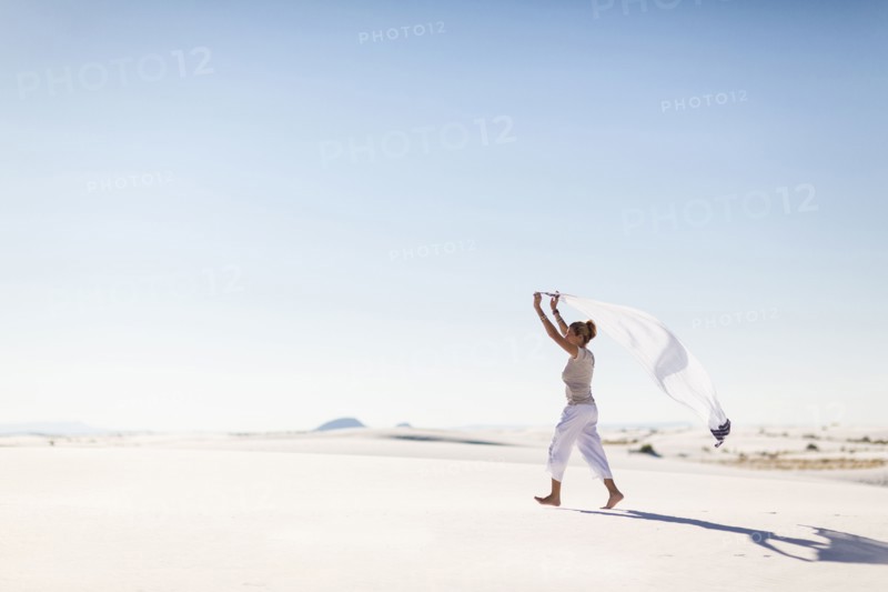 Caucasian woman playing with scarf on sand dune