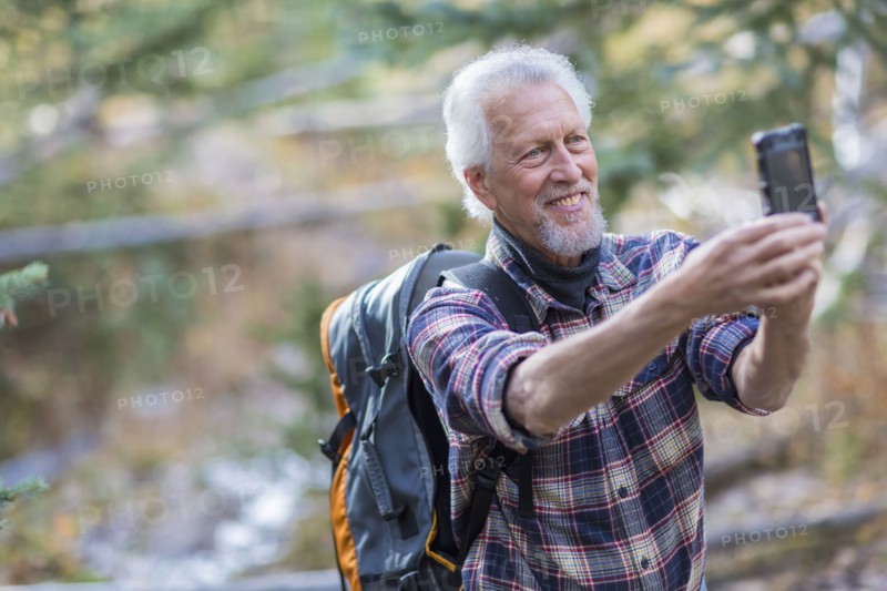 Caucasian hiker taking cell phone photograph in forest