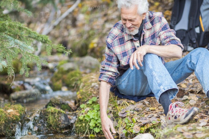 Caucasian hiker dipping fingers in forest creek