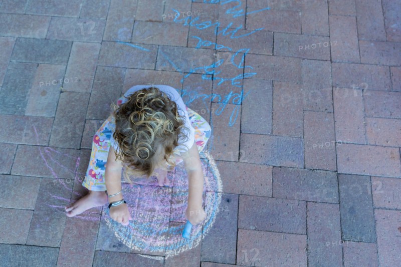 Caucasian boy drawing with chalk on patio