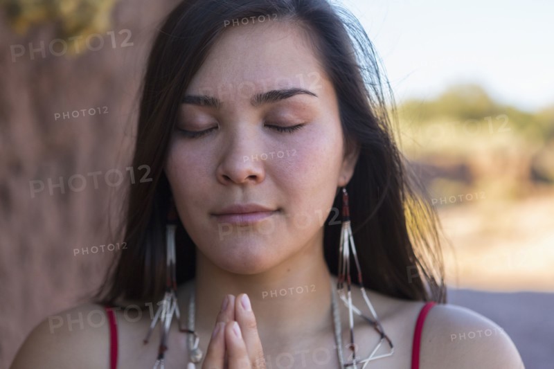 Mixed race woman praying in desert