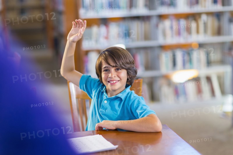 Student raising his hand in library