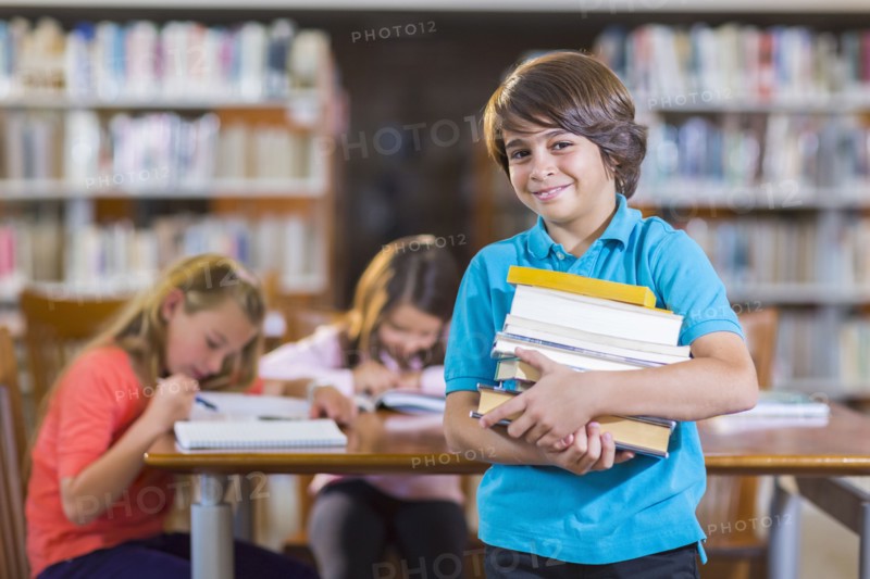 Student carrying stack of books in library
