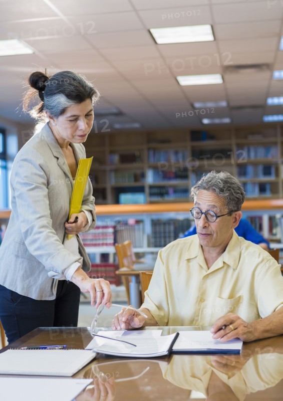 Teacher helping adult student in library