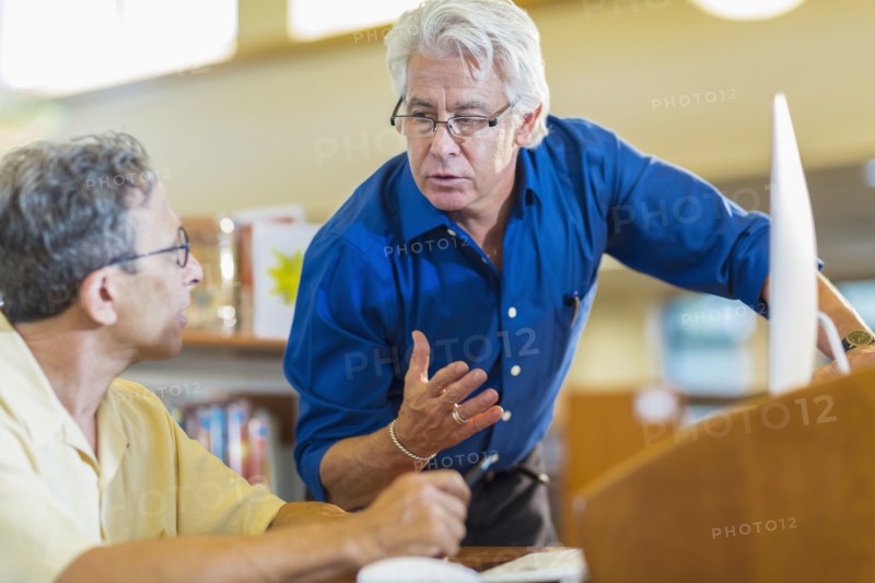 Teacher helping adult student in library